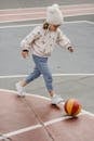 Cute girl walking after ball on sports ground