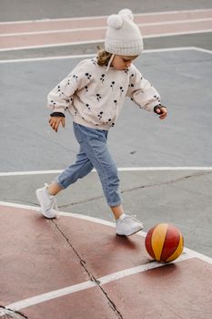 孩子们穿着温暖的服装，在户外运动场上拿着球玩耍