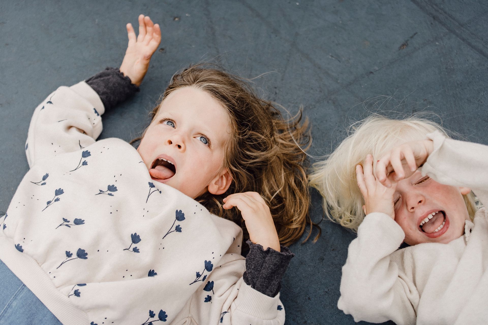 Top view of funny little girl and cute boy with open mouths lying on sports ground while having fun together