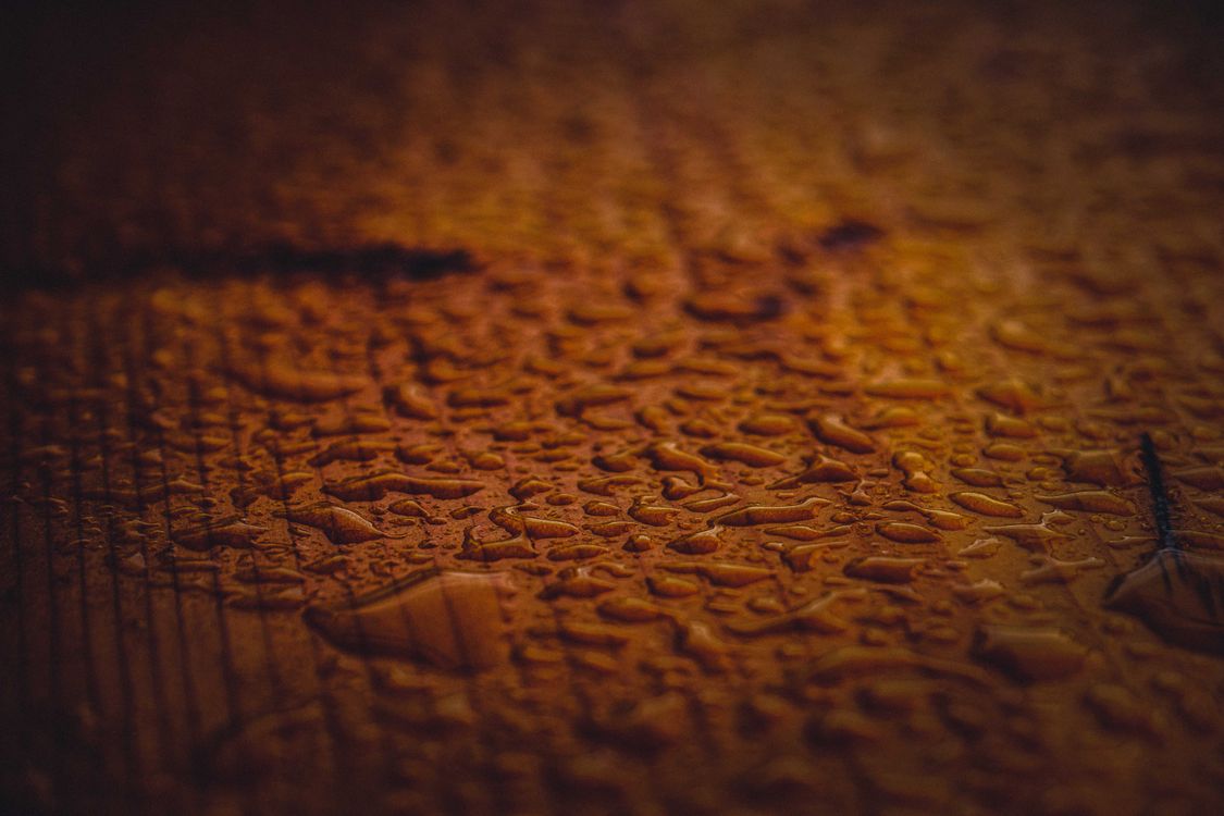 Water droplets scattered across a wooden surface close-up