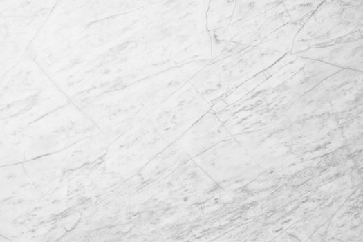 A high-resolution close-up of a white marble surface with natural veining patterns.