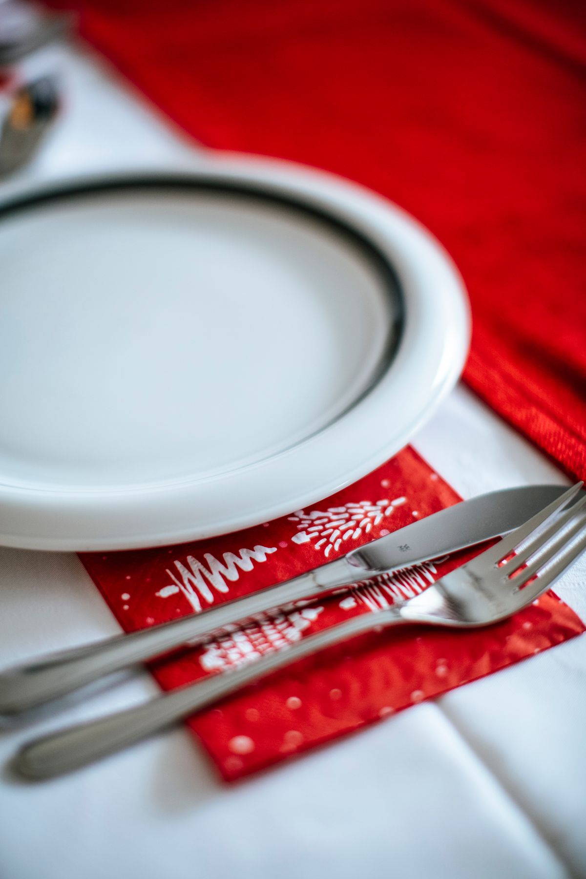 Flat folded Christmas napkin on a plate with a pinecone on top