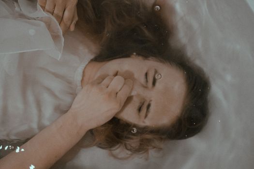 俯视图中，一位女性闭着眼睛和鼻子，躺在清水中沐浴