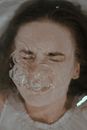 From above of female with closed eyes immersed in water in bathtub forming bubbles on surface while holding breath at home