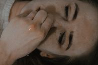 Top view of female with closed eyes lying underwater in bathtub and pinching nose while holding breath at home in bathroom