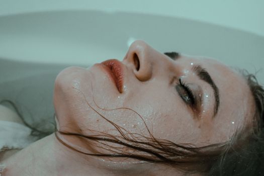 年轻女子闭着眼睛，表情平静地沉浸在浴缸里