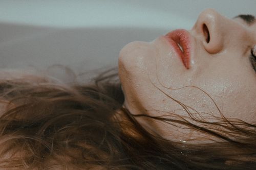 Free Anonymous female resting while lying in bathtub with wet face and hair immersed in water at home in bathroom inside Stock Photo