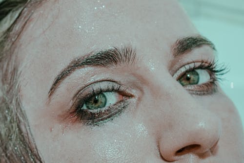 Free Closeup of anonymous female with wet face and mascara under eyes looking at camera while lying in bathtub Stock Photo