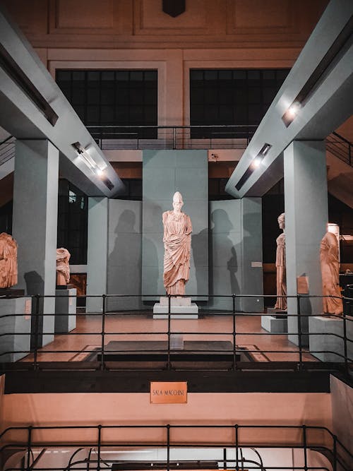 Interior of Centrale Montemartini archeological museum with exhibition of ancient Roman statues under lights on roof