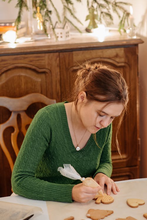 Woman in Green Cardigan Decorating A Cookie