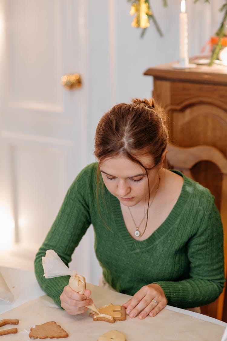 Woman In Green Long Sleeve Shirt Putting Icing On A Cookie