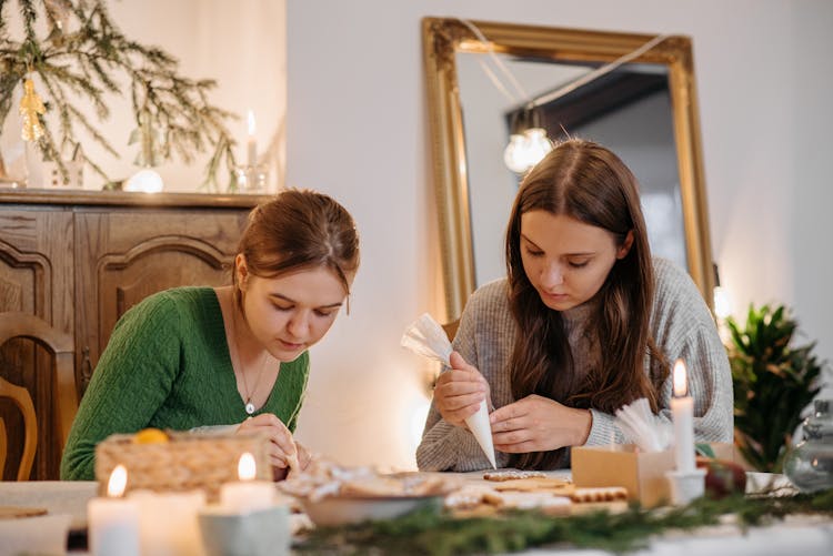 Two Girls Putting Icing On Cookies