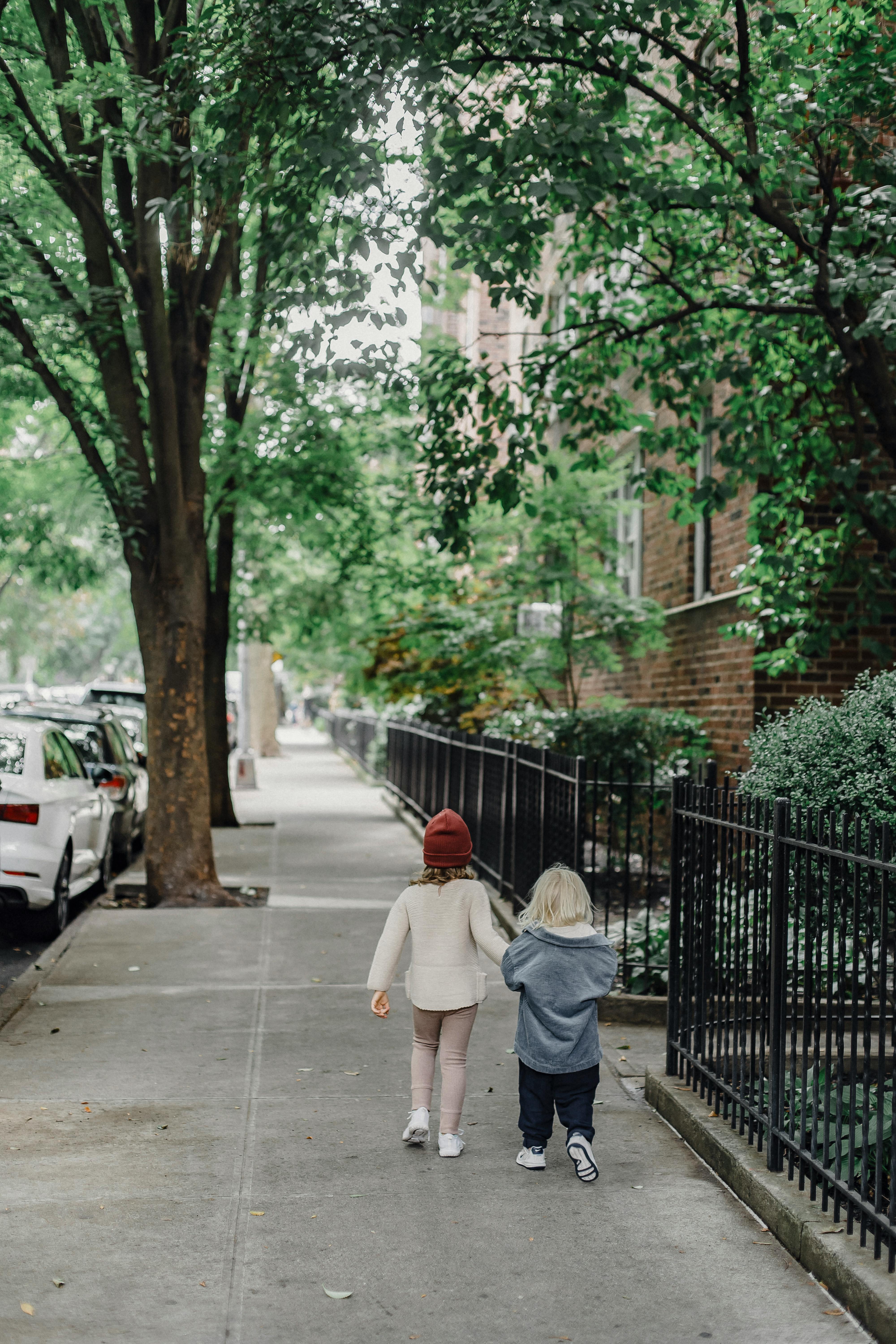 unrecognizable siblings walking on sidewalk