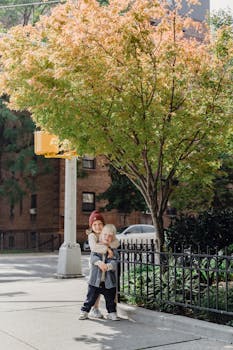 在阳光明媚的城市街道旁，可爱的兄弟姐妹在一棵树下相拥，流露出欢乐与纯真