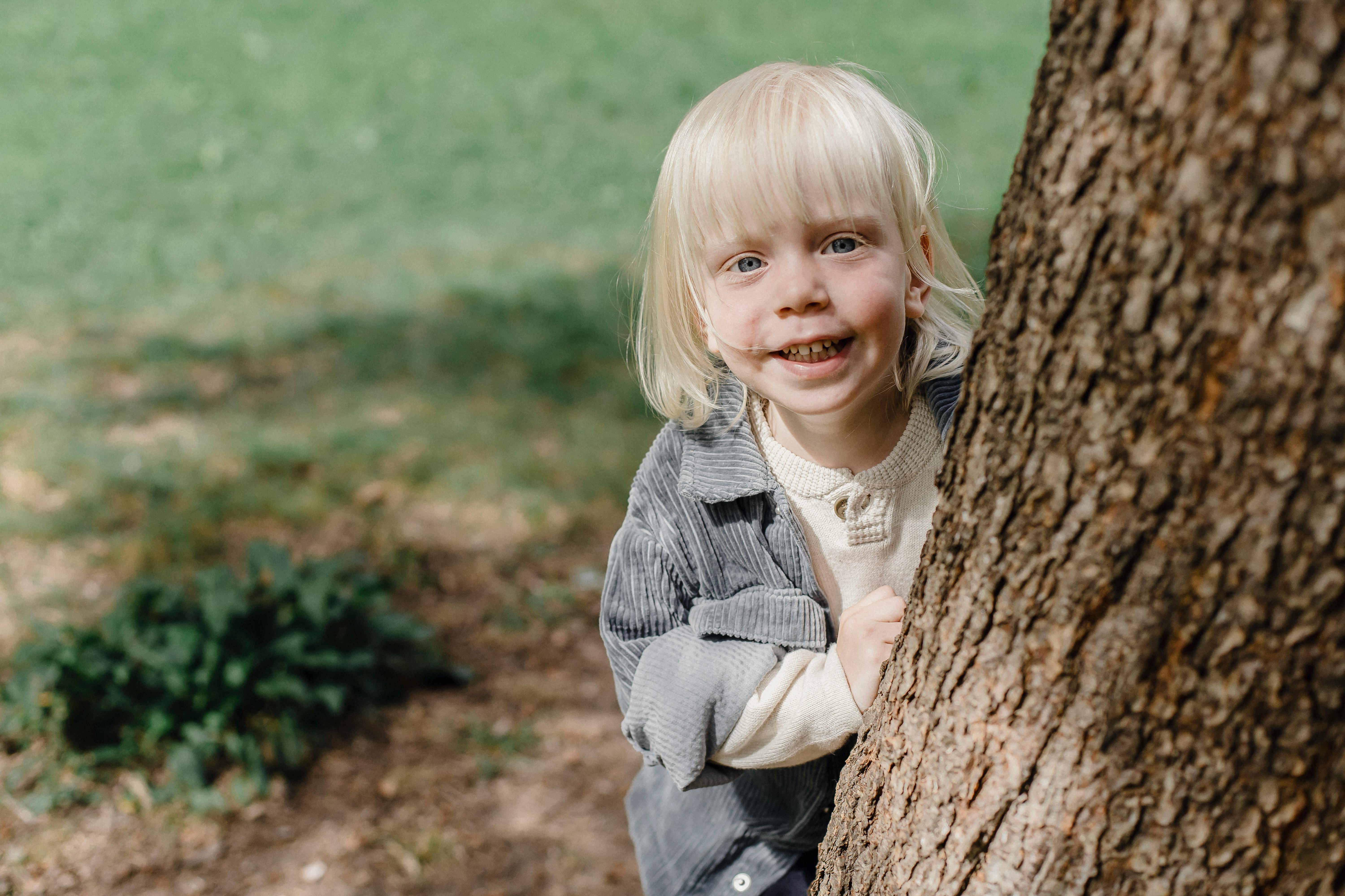 cheerful little boy standing near tree