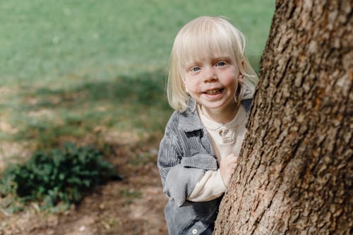 Cheerful little boy standing near tree