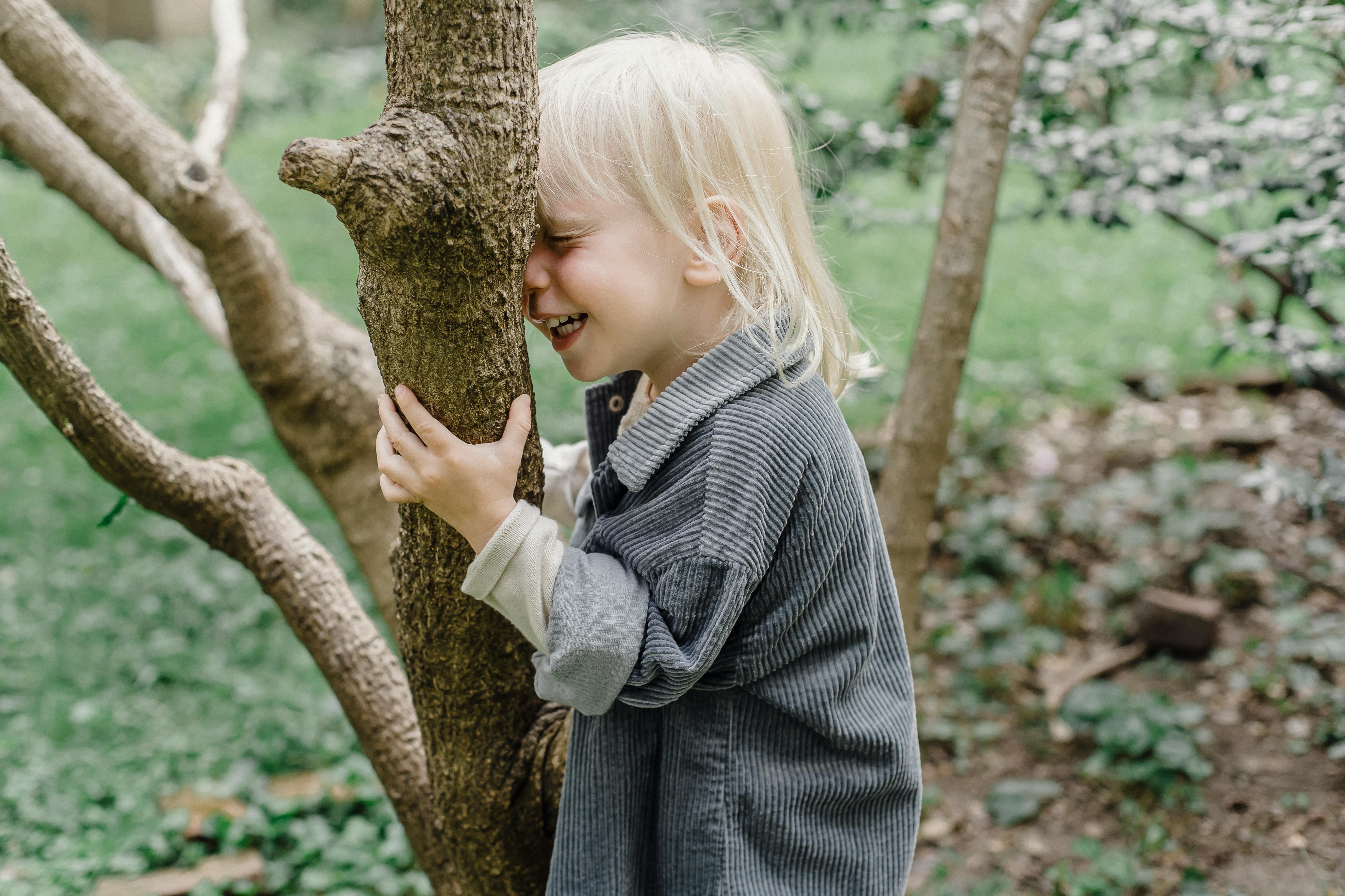 happy little bߋy standing near tгᥙnk