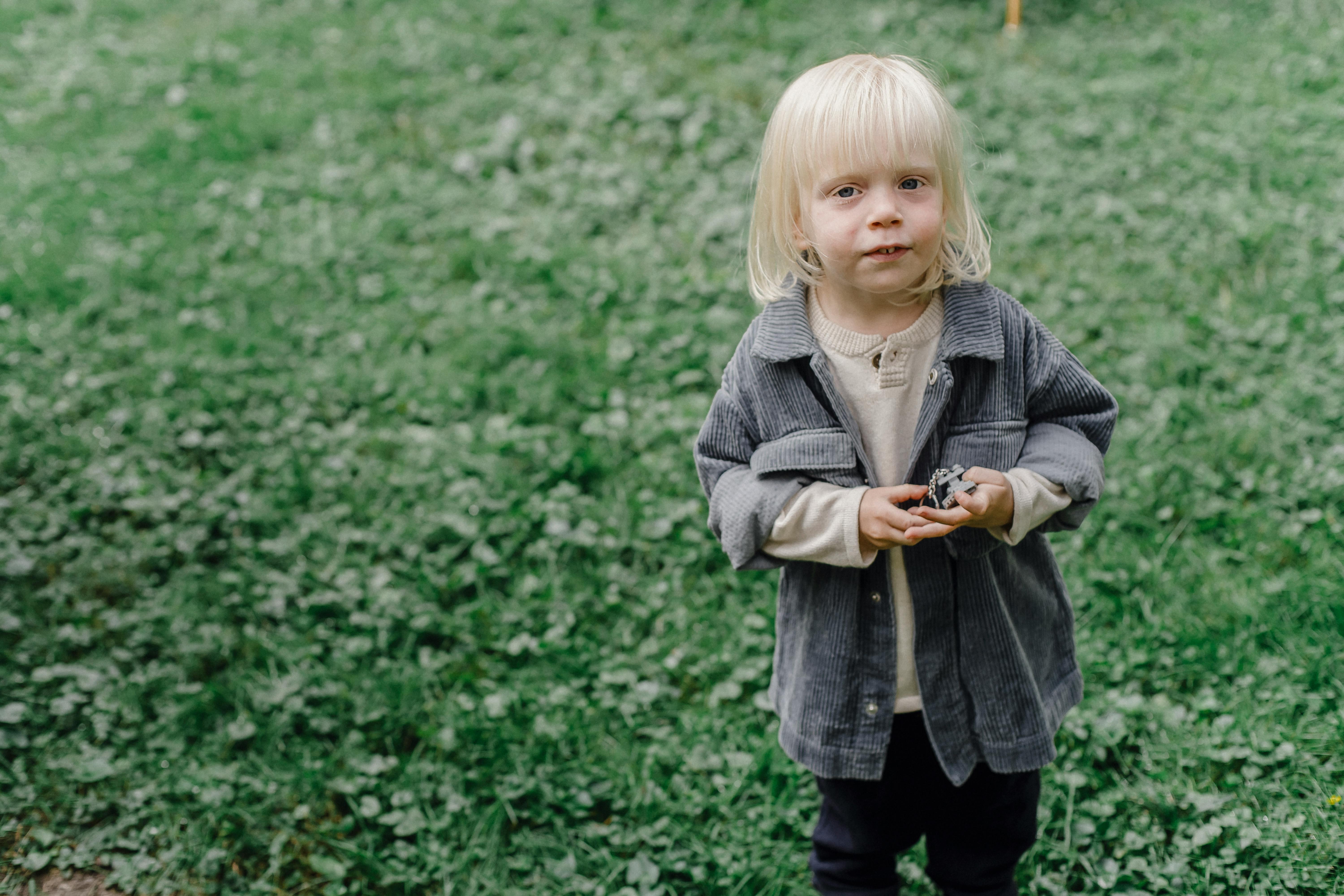 Blond child enjoying playtime in a green meadow, embracing the joys of nature.
