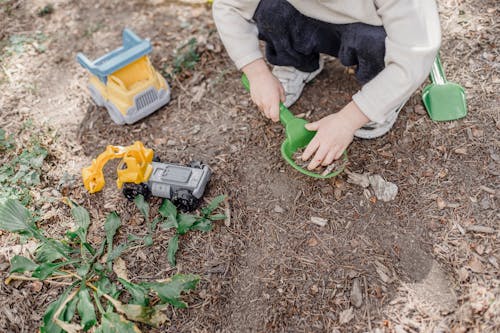 Little kid playing in garden with toys