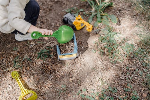 Little kid playing with plastic colourful toys in yard