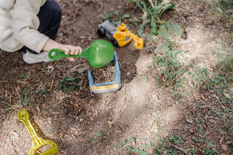 Little Kid Playing With Plastic Colourful Toys In Yard