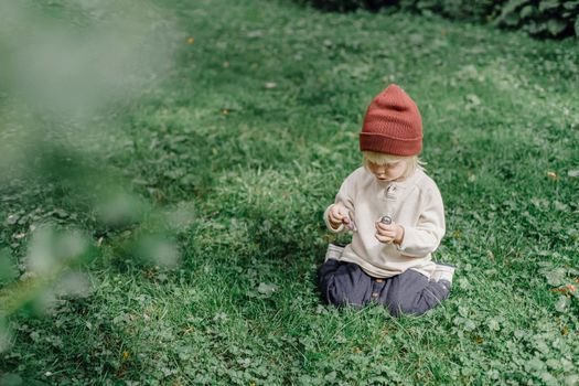 夏日阳光明媚，一个穿着休闲服装、戴着棕色帽子的小男孩，正专注地在院子里玩耍