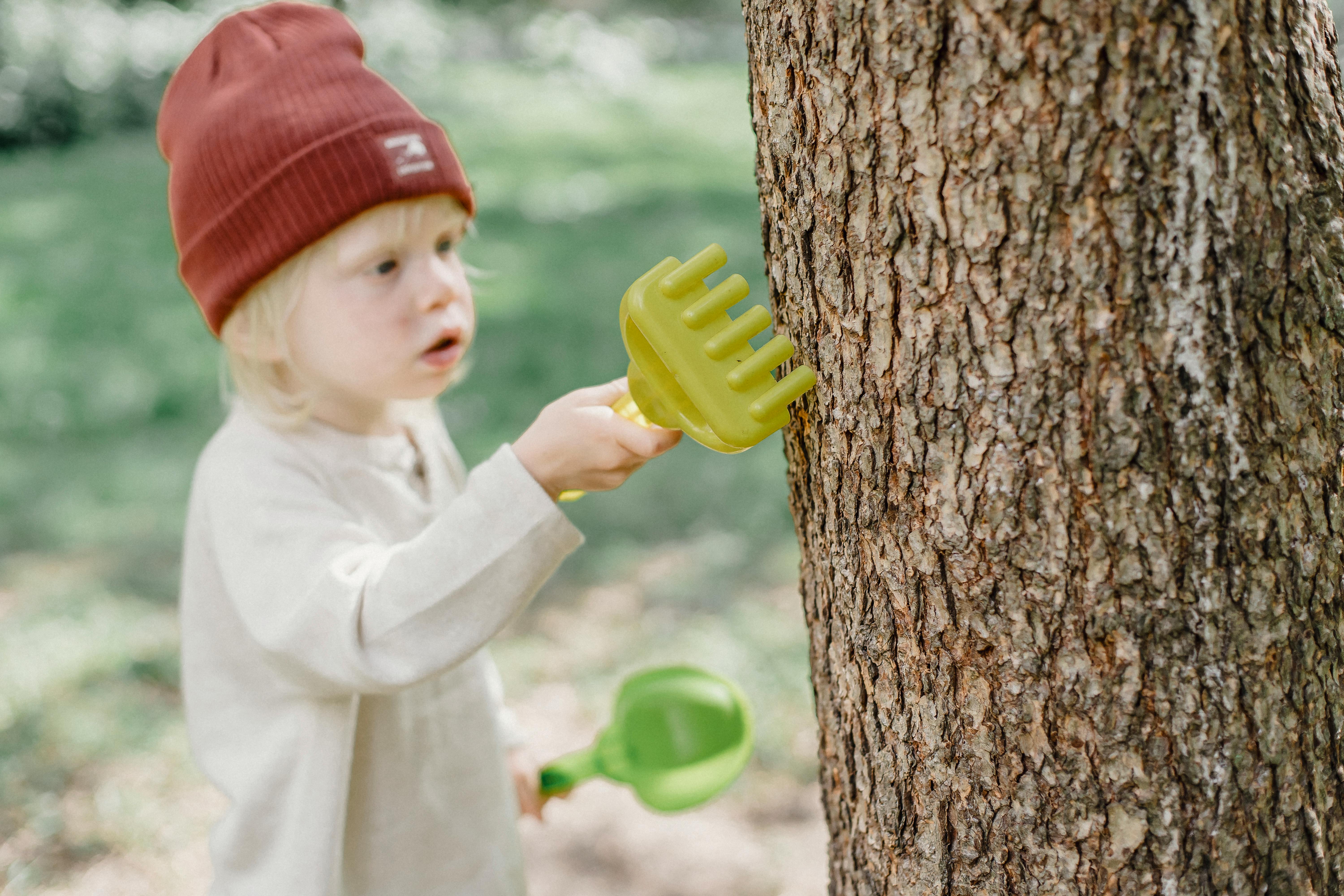 little boy playing with toys near big tree