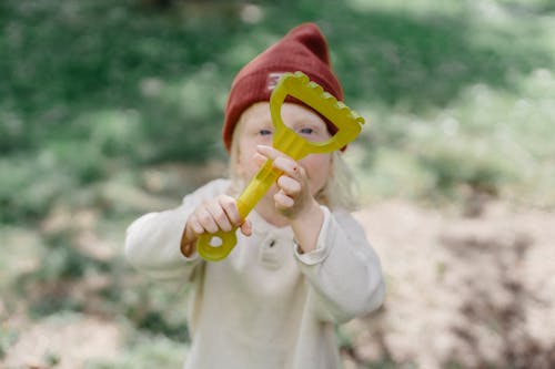 Little boy playing with toy rake in sunny summer day