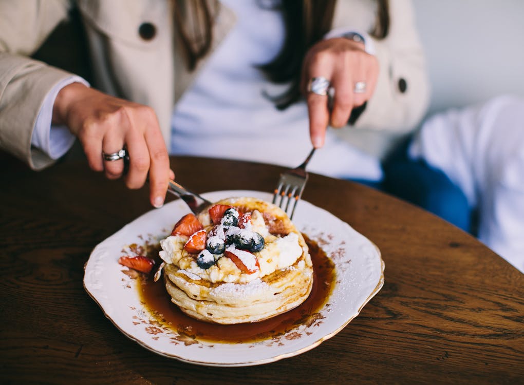 Free Person Eating Pancakes with Fresh Fruits Stock Photo