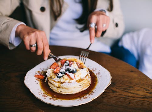 Free Person Eating Pancakes with Fresh Fruits Stock Photo