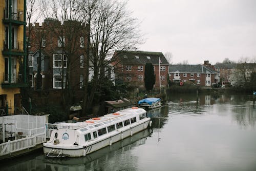 White Boat on the River Near Apartment Buildings