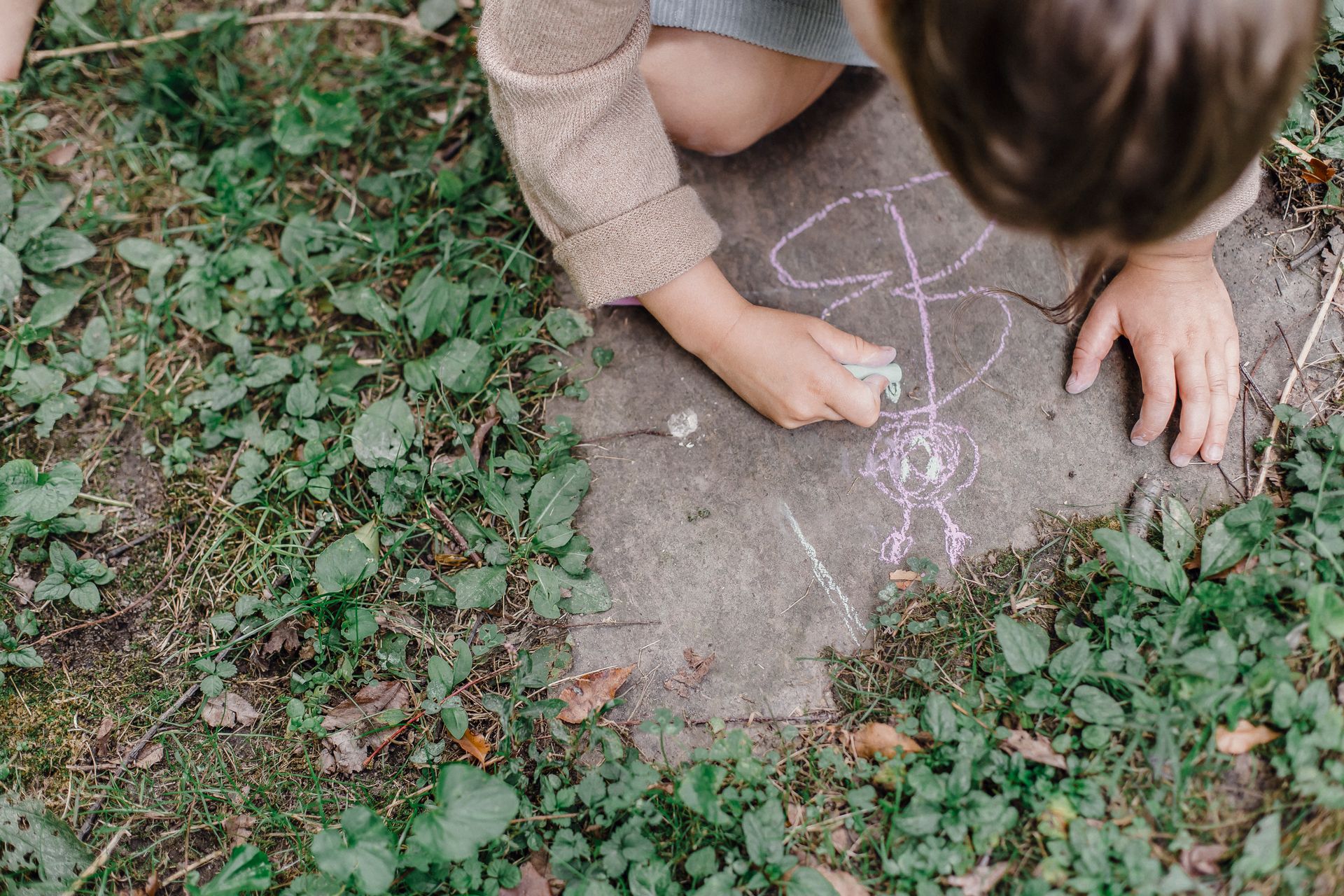 Child drawing with chalk on a path