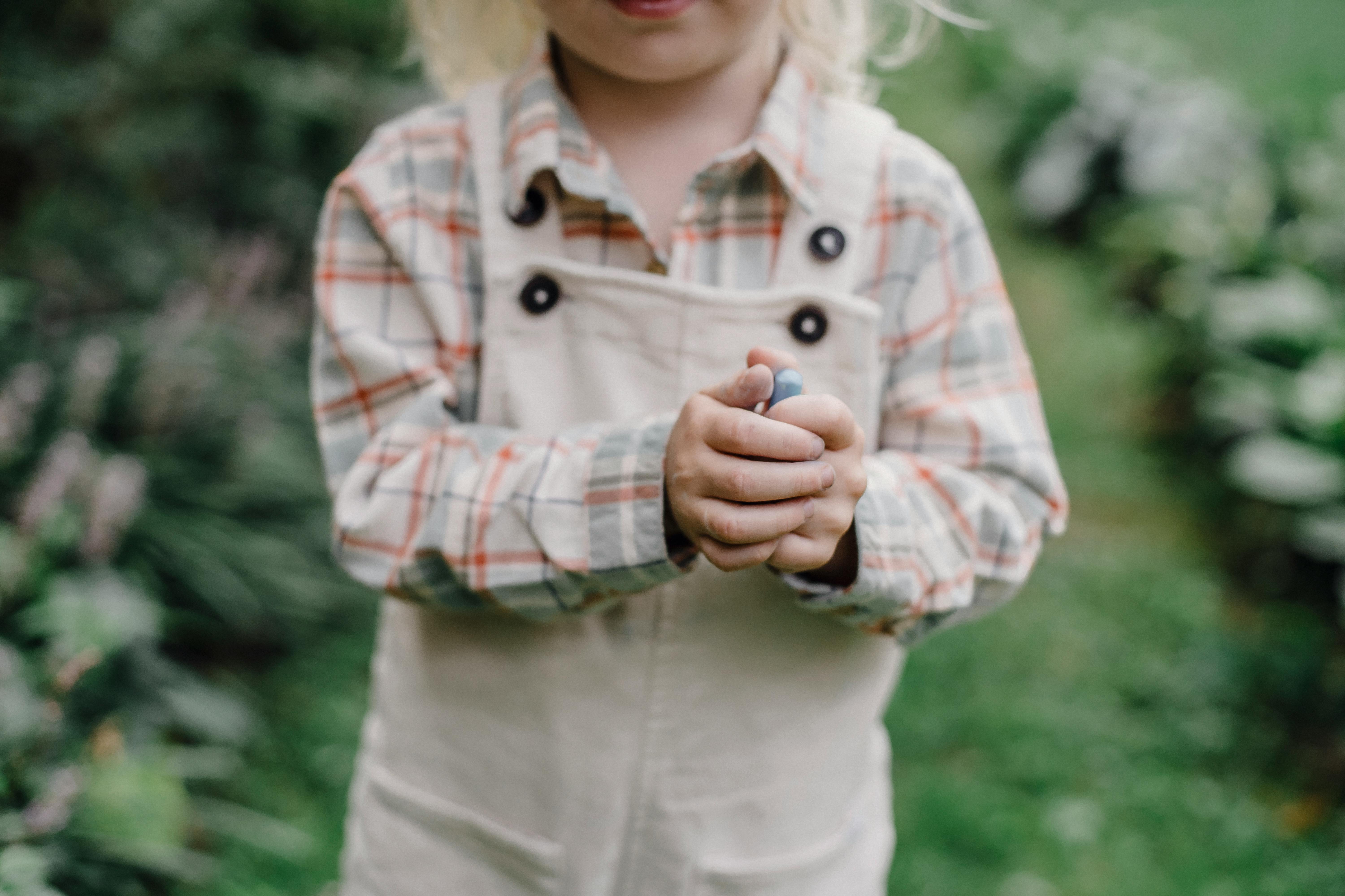 faceless child showing picked berry in green garden