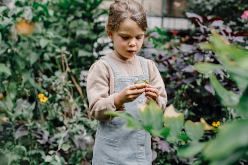 Thoughtful kid exploring fresh fruit in garden