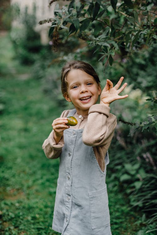 Cute smiling girl with feijoa near green bush