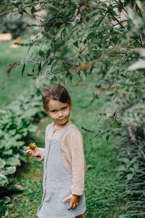 Little cute girl with feijoa near green shrub