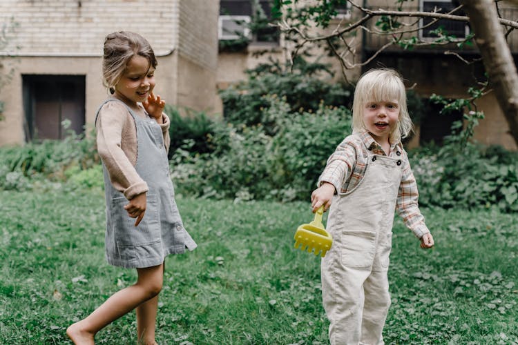 Happy Children Playing With Plastic Rake In Yard