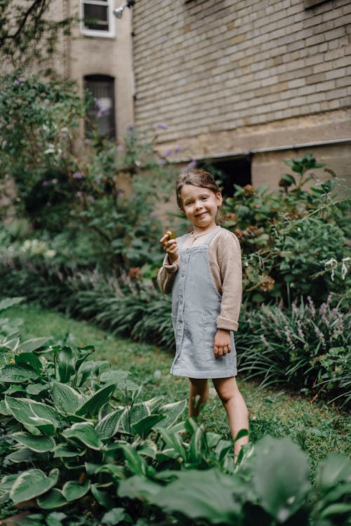 Cute happy girl with feijoa on green lawn with plants