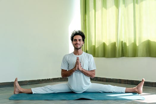 Man practicing yoga indoors with a calm and focused expression, highlighting flexibility and mindfulness.
