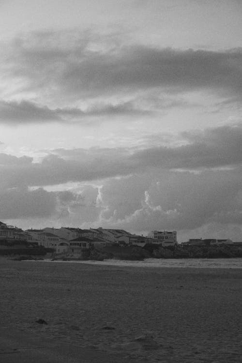 Grayscale Photo of Buildings Near a Beach