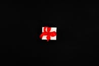 白色礼品盒系着红丝带，衬在黑色背景上，非常适合庆祝活动