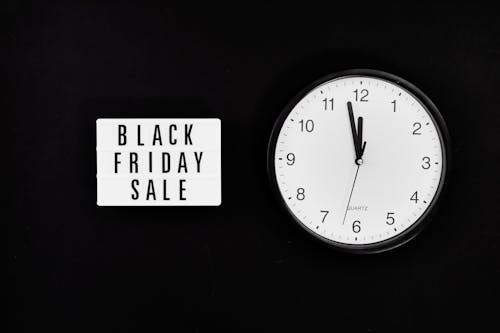A Black Friday Sale Signage Beside a Black and White Round Analog Wall Clock