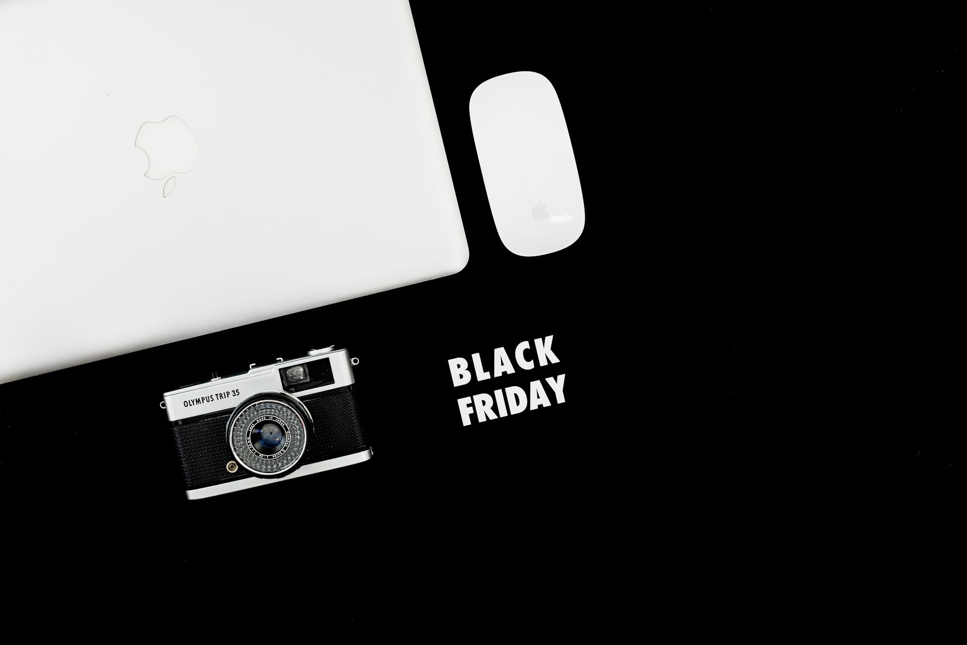 Stylish flat lay of laptop, camera, and mouse with Black Friday text.