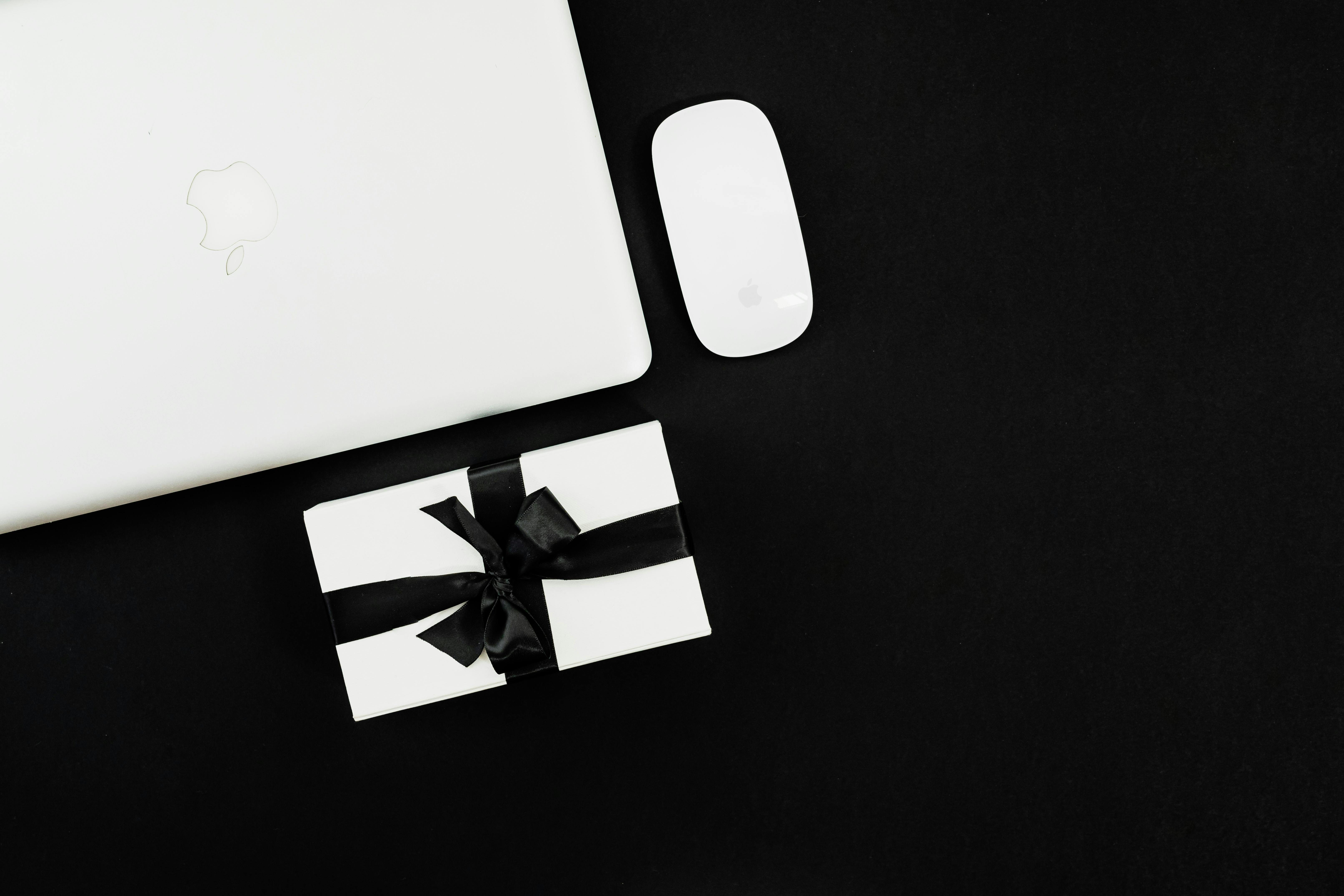 white apple magic mouse beside silver macbook on black background