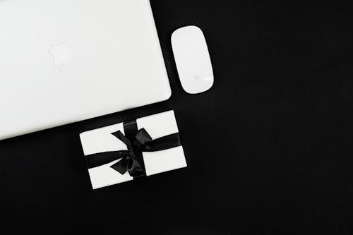 White Apple Magic Mouse Beside Silver Macbook On Black Background