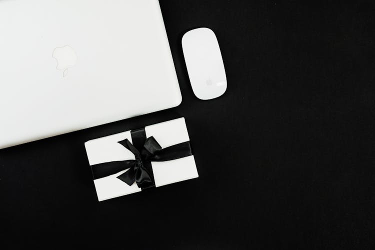 White Apple Magic Mouse Beside Silver Macbook On Black Background