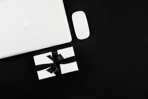 Free Flat lay of a laptop, mouse, and gift box, ideal for Black Friday online shopping theme. Stock Photo