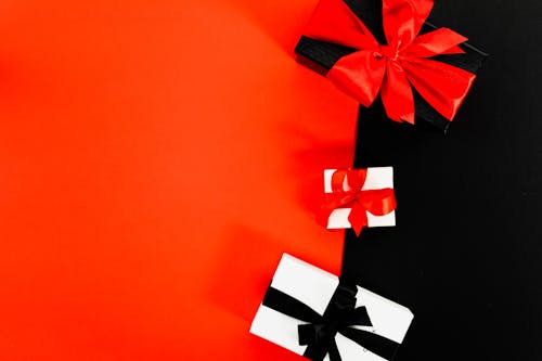 Three Boxes Tied With Ribbons on Red and Black Background