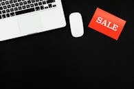 Macbook Pro Beside Red and White Sale Card