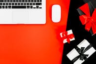 红色背景上的平板电脑与礼品盒，构成了完美的假日购物主题